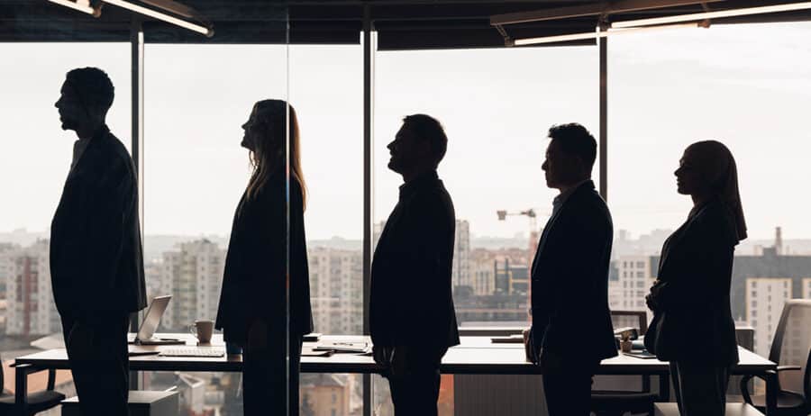 Silhouette photo of a group of businessmen standing side by side in profile in office